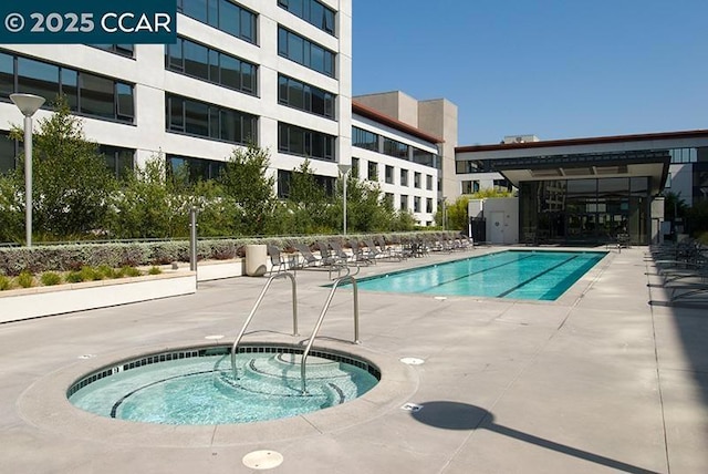 view of swimming pool featuring a hot tub and a patio area