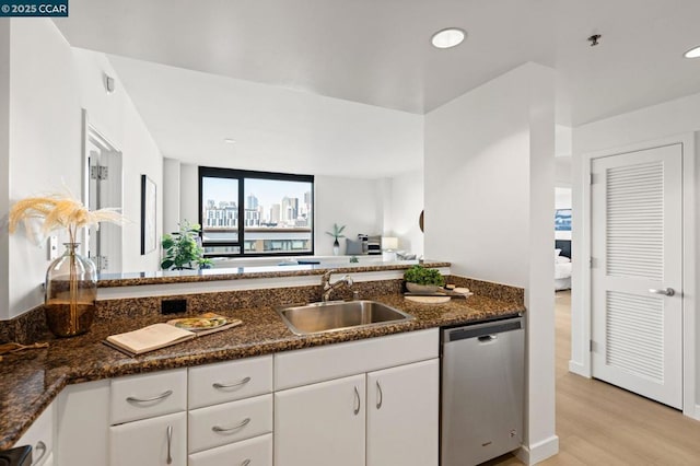 kitchen featuring light hardwood / wood-style floors, sink, white cabinetry, and stainless steel dishwasher