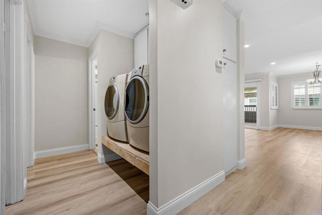 clothes washing area with crown molding, separate washer and dryer, a chandelier, and light hardwood / wood-style flooring