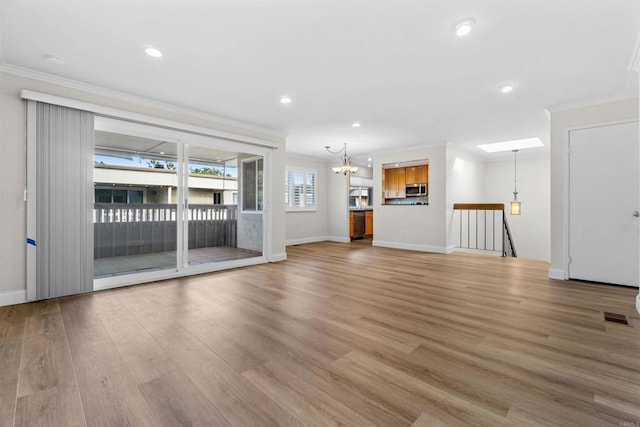 unfurnished living room featuring a chandelier, crown molding, and light hardwood / wood-style floors