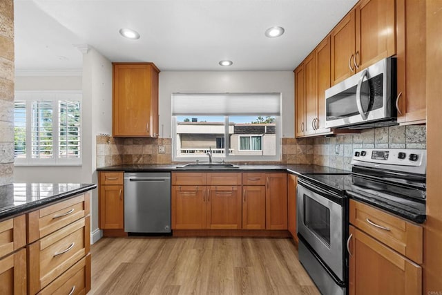 kitchen with dark stone countertops, decorative backsplash, sink, light hardwood / wood-style flooring, and stainless steel appliances