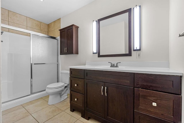 bathroom with a shower with shower door, vanity, tile patterned flooring, and toilet