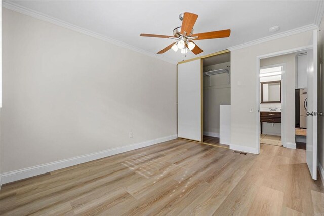 unfurnished bedroom featuring crown molding, light hardwood / wood-style flooring, a closet, ceiling fan, and stacked washing maching and dryer