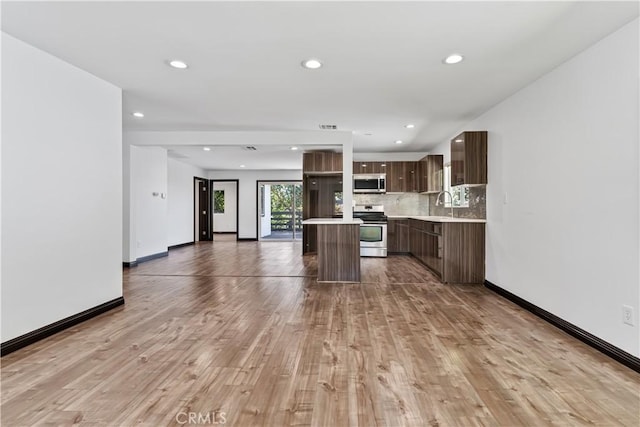 kitchen with a kitchen island, stainless steel appliances, light hardwood / wood-style floors, sink, and backsplash