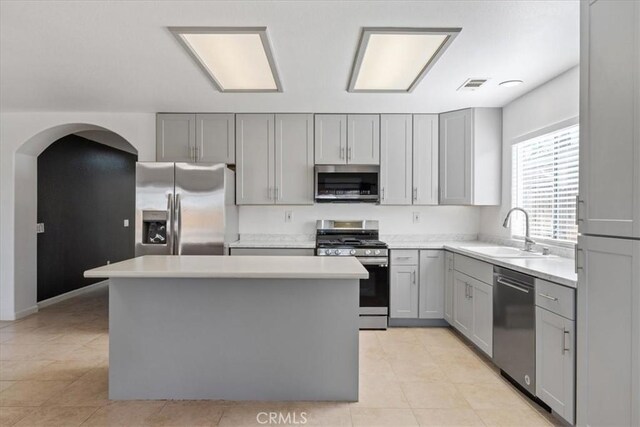 kitchen with sink, a center island, stainless steel appliances, and gray cabinetry