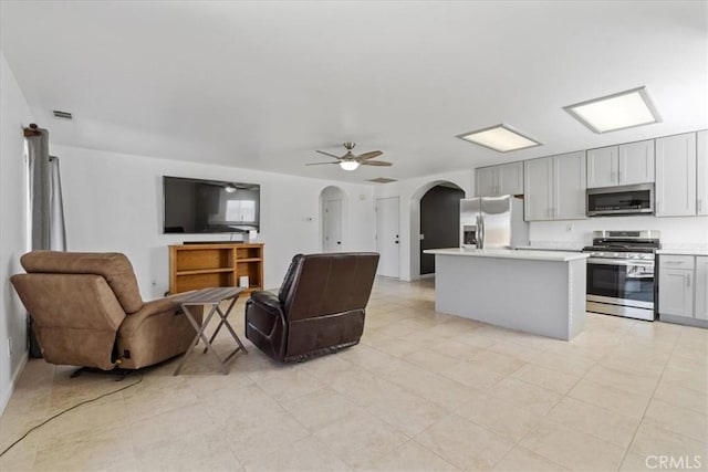 kitchen featuring ceiling fan, appliances with stainless steel finishes, a center island, and gray cabinetry