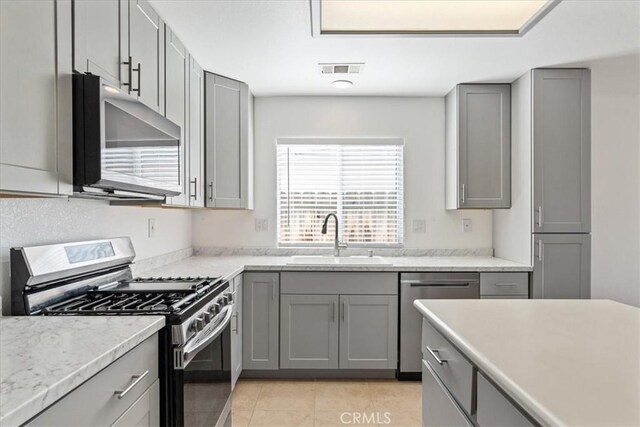 kitchen featuring sink, gray cabinets, stainless steel appliances, and light tile patterned flooring