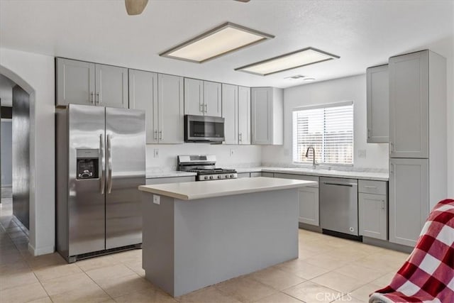 kitchen with light tile patterned floors, appliances with stainless steel finishes, a kitchen island, and sink