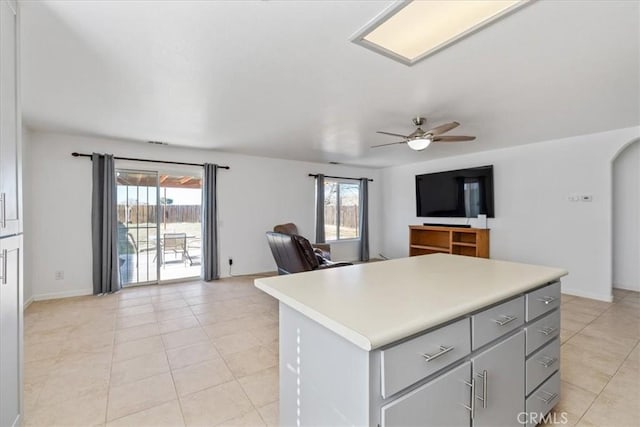 kitchen featuring ceiling fan, a healthy amount of sunlight, gray cabinets, and a center island