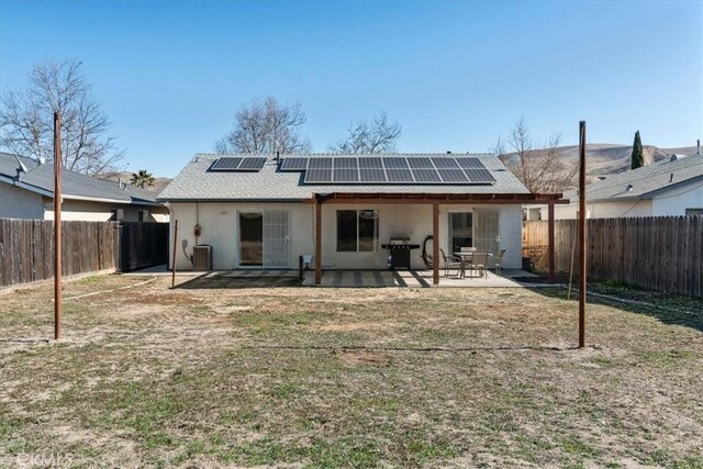 back of house with central AC unit, a patio area, and solar panels