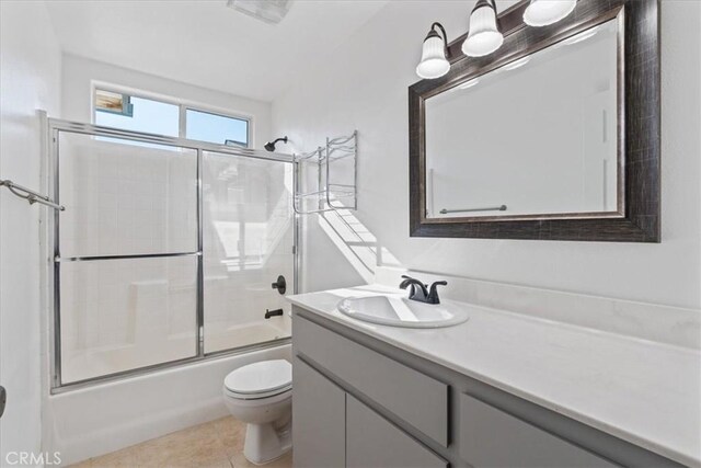 full bathroom with tile patterned floors, shower / bath combination with glass door, vanity, and toilet