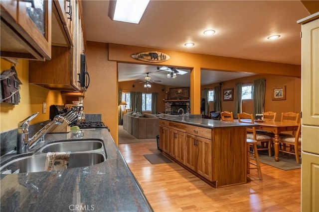 kitchen with kitchen peninsula, a breakfast bar area, ceiling fan, a fireplace, and sink