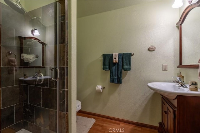 bathroom featuring toilet, vanity, a shower with door, and hardwood / wood-style flooring