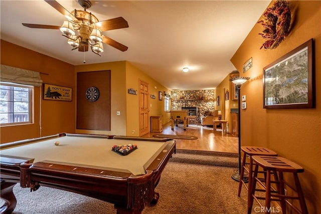 game room featuring ceiling fan, pool table, carpet floors, and a stone fireplace