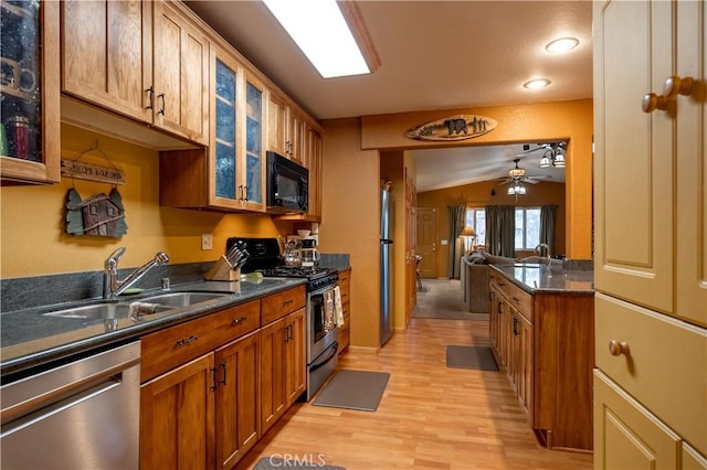 kitchen featuring light hardwood / wood-style floors, ceiling fan, appliances with stainless steel finishes, lofted ceiling, and sink