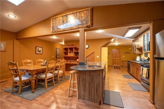 dining room featuring sink, light hardwood / wood-style flooring, and vaulted ceiling