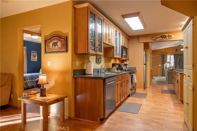 kitchen featuring lofted ceiling, stainless steel appliances, light hardwood / wood-style floors, sink, and ceiling fan