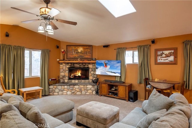 carpeted living room featuring ceiling fan, a stone fireplace, and vaulted ceiling