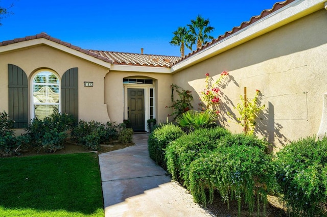 view of exterior entry with a lawn