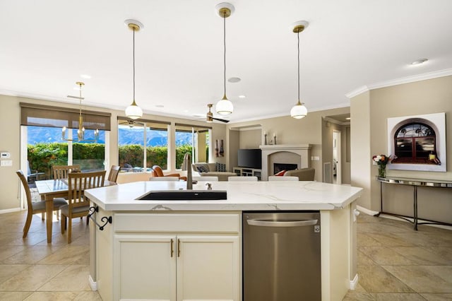 kitchen with decorative light fixtures, an island with sink, sink, ceiling fan, and light stone counters