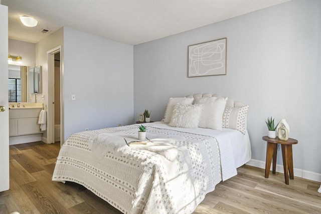 bedroom featuring sink, light hardwood / wood-style flooring, and ensuite bath