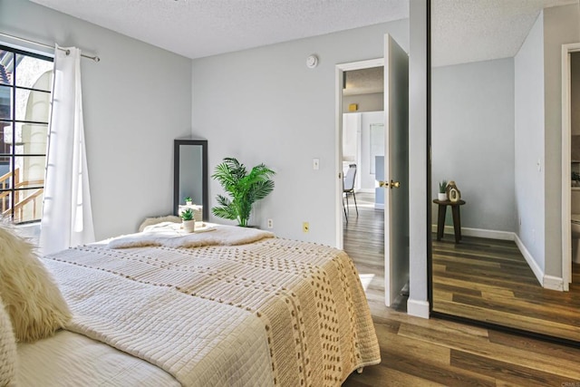 bedroom with a textured ceiling and dark wood-type flooring