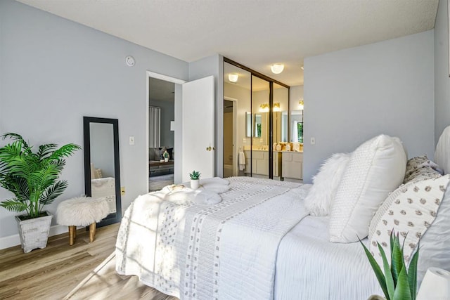 bedroom featuring a closet, connected bathroom, and light hardwood / wood-style flooring