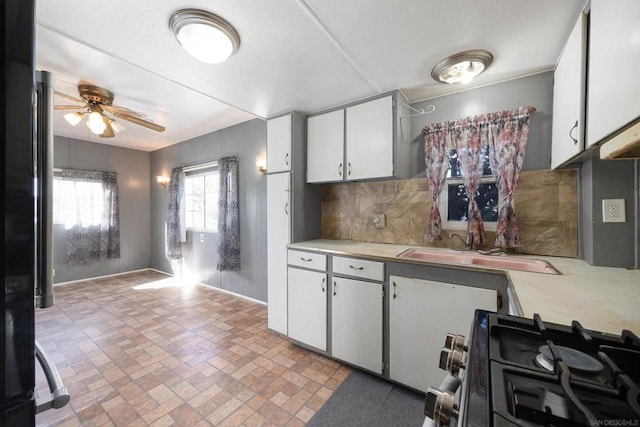 kitchen with white cabinets, tasteful backsplash, sink, ceiling fan, and stainless steel range with gas stovetop