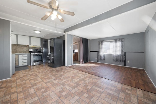 kitchen with black refrigerator, white cabinetry, stainless steel gas stove, decorative backsplash, and ceiling fan