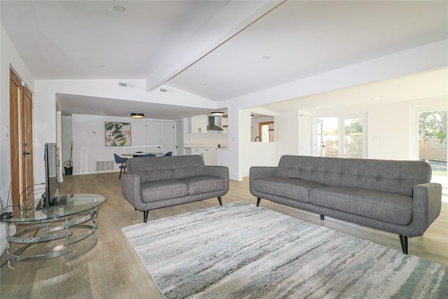 living room with light hardwood / wood-style floors and lofted ceiling with beams