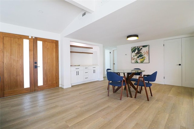 dining area featuring vaulted ceiling with beams and light hardwood / wood-style flooring