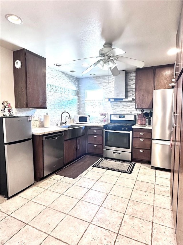 kitchen featuring sink, dark brown cabinetry, appliances with stainless steel finishes, and wall chimney exhaust hood