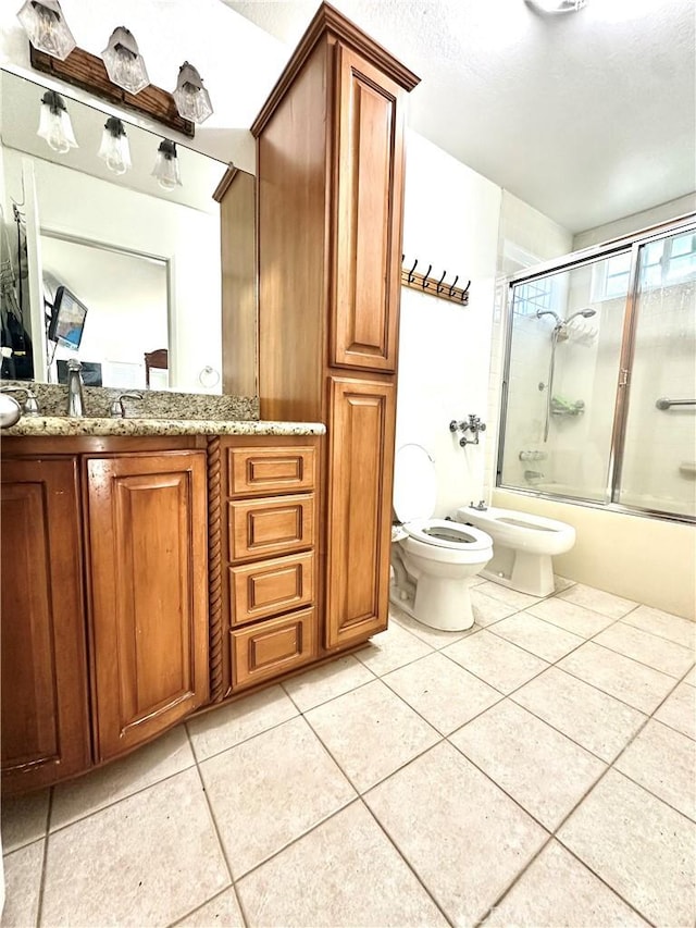 full bathroom featuring toilet, combined bath / shower with glass door, a bidet, tile patterned flooring, and vanity