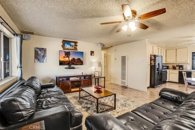 living area featuring a ceiling fan, visible vents, a textured ceiling, and light tile patterned floors