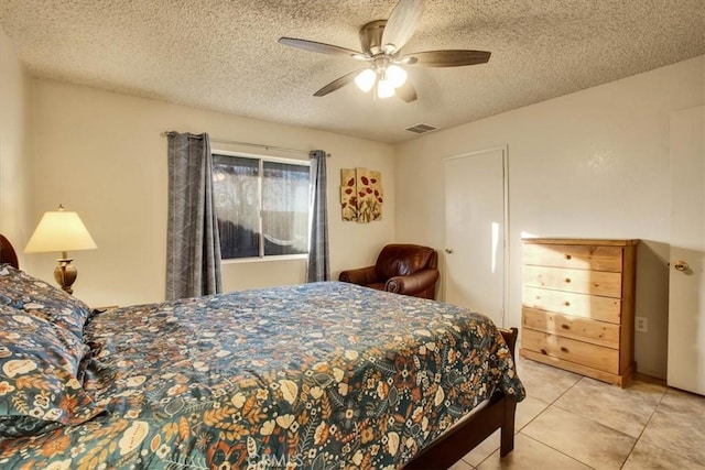 bedroom with a textured ceiling, light tile patterned flooring, visible vents, and a ceiling fan