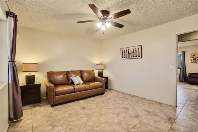 living room with a textured ceiling, ceiling fan, and light tile patterned flooring