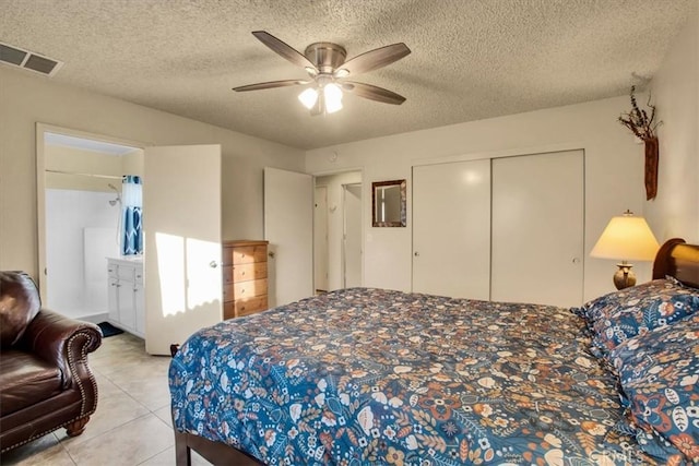 bedroom featuring a textured ceiling, light tile patterned flooring, visible vents, a ceiling fan, and a closet