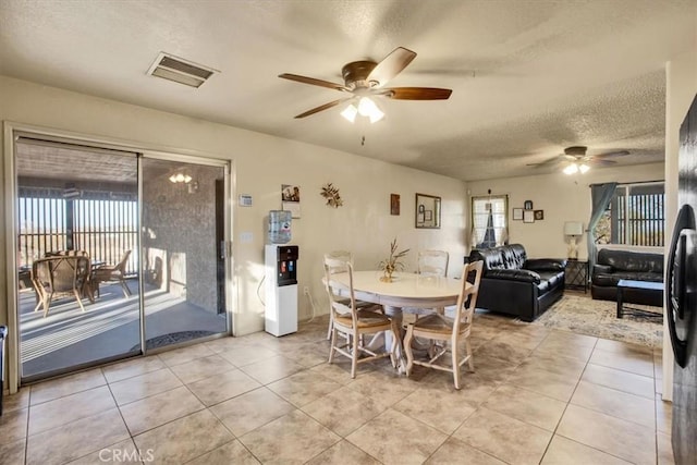 tiled dining room with ceiling fan, a healthy amount of sunlight, and a textured ceiling