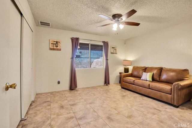 tiled living room featuring a textured ceiling and ceiling fan