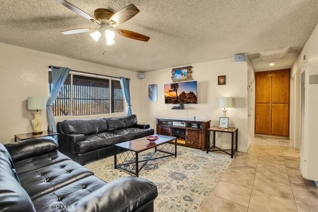 living room with a textured ceiling, ceiling fan, and light tile patterned flooring