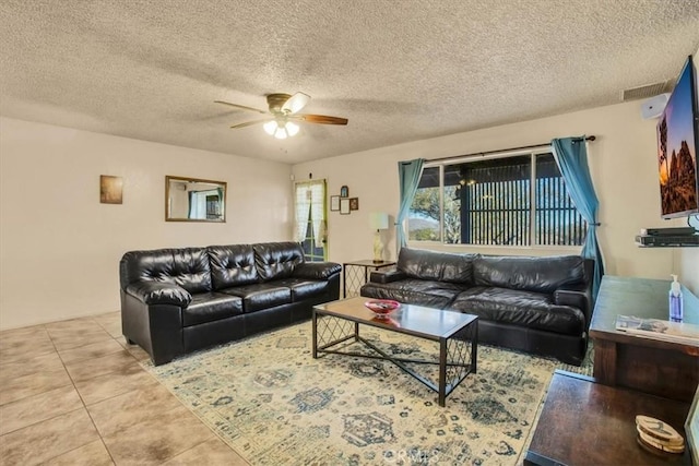 living room with ceiling fan, a textured ceiling, and light tile patterned flooring