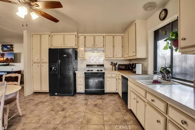 kitchen with cream cabinetry, light countertops, a sink, under cabinet range hood, and black appliances