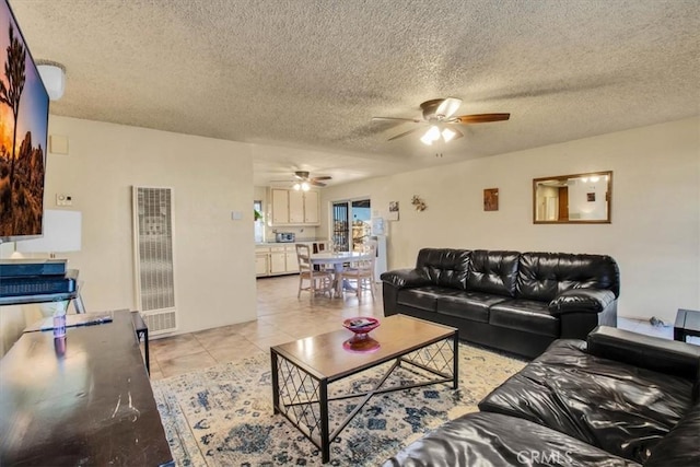 living room with light tile patterned floors, a textured ceiling, and a ceiling fan