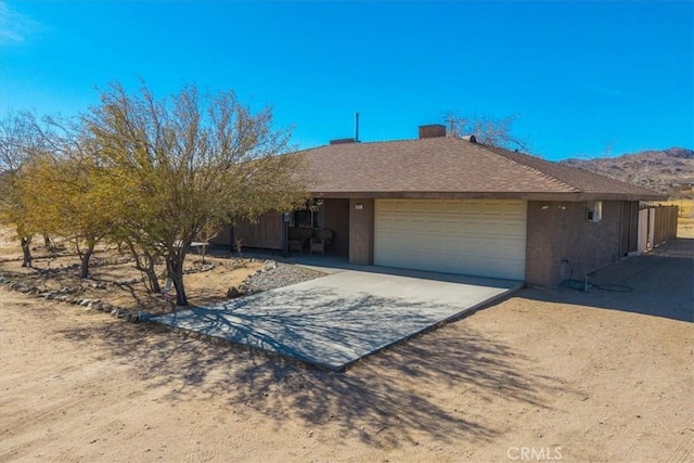 single story home featuring concrete driveway, roof with shingles, an attached garage, and stucco siding