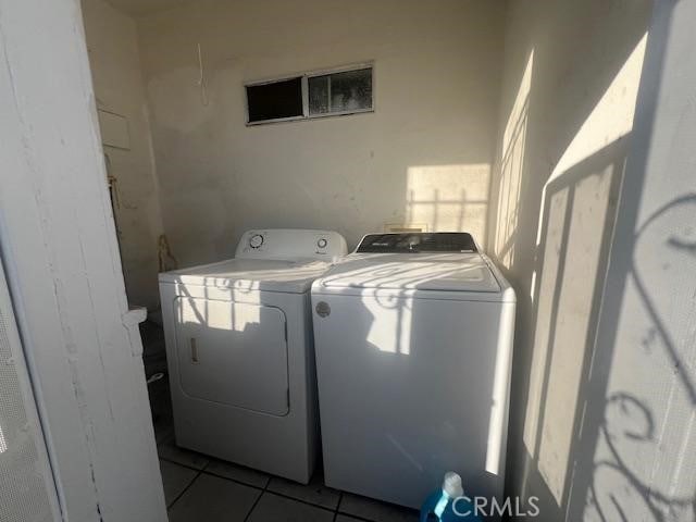 clothes washing area with washer and clothes dryer and light tile patterned floors