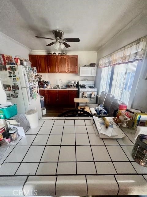 interior space with sink, white appliances, crown molding, and tile counters