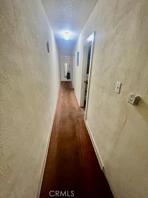 corridor with dark hardwood / wood-style floors and a textured ceiling