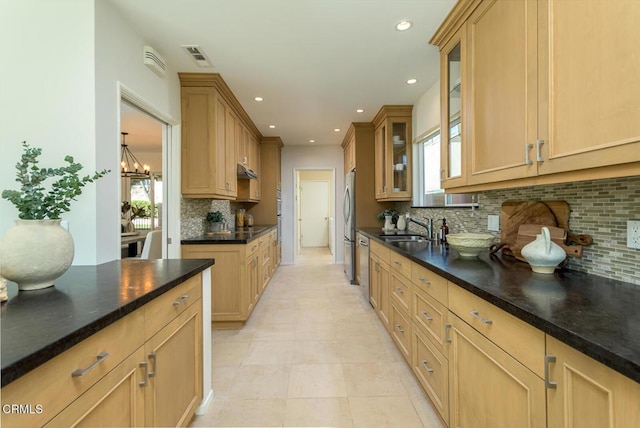 kitchen featuring sink, backsplash, appliances with stainless steel finishes, and an inviting chandelier