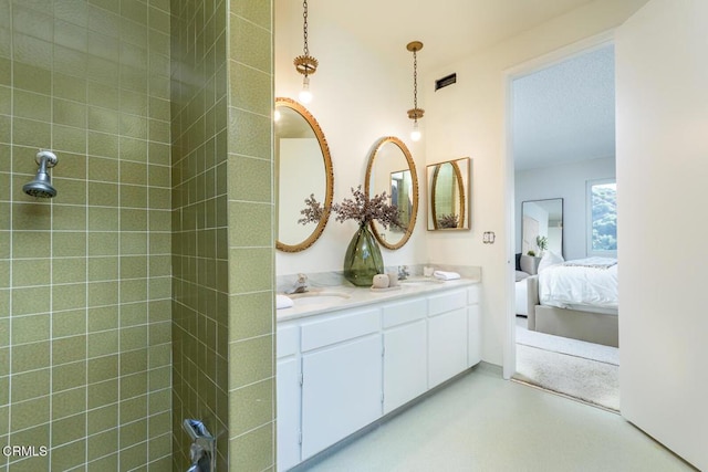 bathroom with a tile shower and vanity