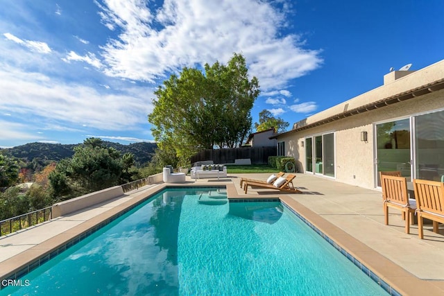 view of pool featuring an outdoor living space, a mountain view, and a patio